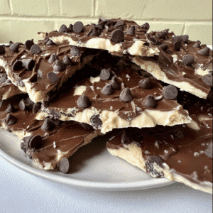 Plate of cookie dough bark layered with white and milk chocolate and topped with chocolate chips