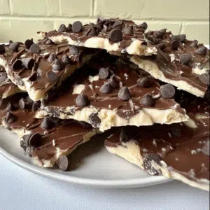 Plate of cookie dough bark layered with white and milk chocolate and topped with chocolate chips