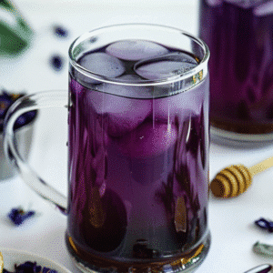 Butterfly Pea Flower Tea with lime, honey, and dried flowers on a white background