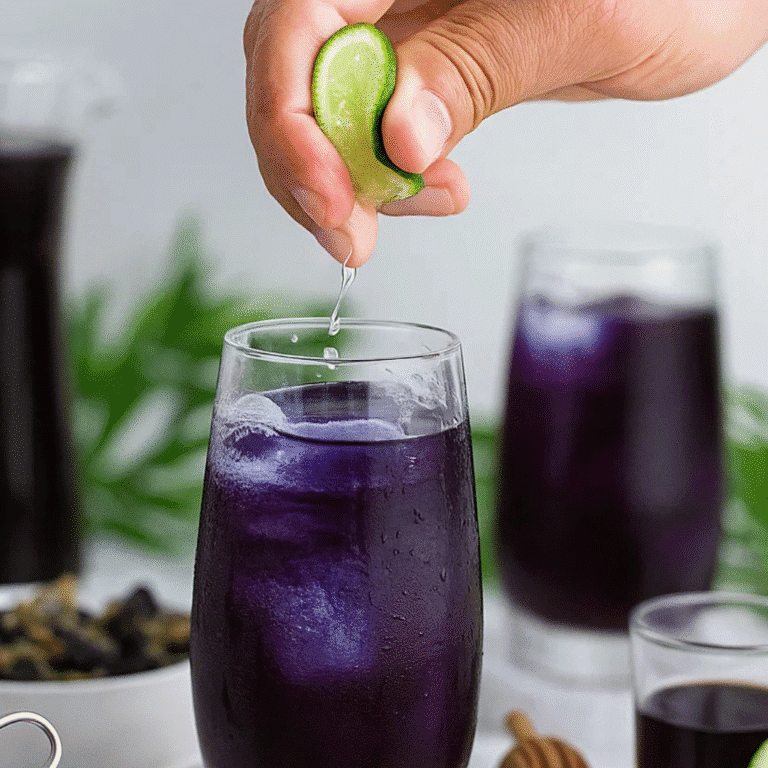 Hand squeezing fresh lime into iced Butterfly Pea Flower Tea for a vibrant color transformation