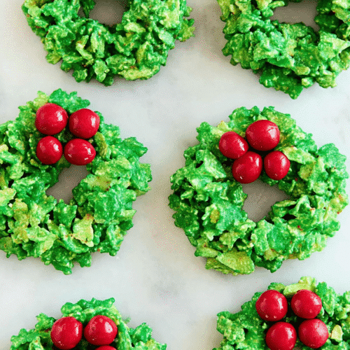 Bright green no-bake cornflake wreaths with red candy holly on marble surface