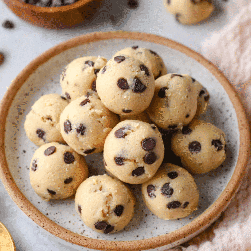 Stacked cottage cheese cookie dough bites with chocolate chips in a ceramic bowl on marble background