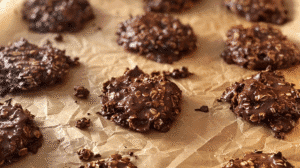 Vintage no bake chocolate drop cookies made with oats, cocoa, and peanut butter cooling on parchment paper.