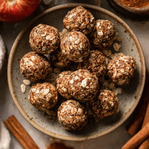 Apple cinnamon energy bites in a rustic bowl with oats, apples, and cinnamon sticks.