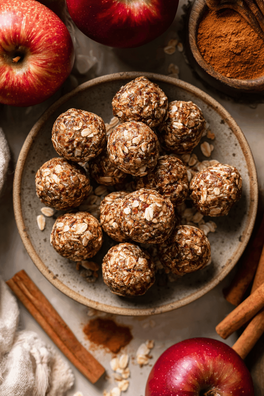 Apple cinnamon energy bites in a rustic bowl with oats, apples, and cinnamon sticks.