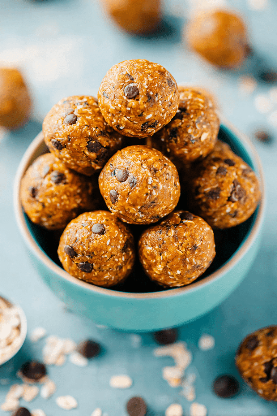 Pumpkin spice energy balls with oats and chocolate chips stacked in a teal bowl
