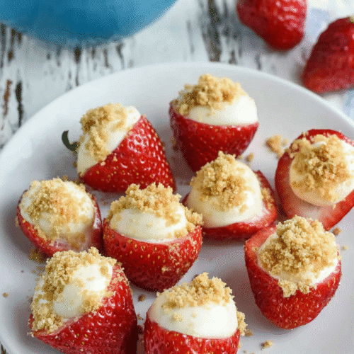 Strawberry cheesecake bites with cream cheese filling and graham cracker crumbs on a rustic table