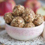 Apple pie energy bites made from oats, dates, and walnuts in a ceramic bowl on a wooden table
