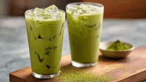 Iced protein matcha latte in tall glasses with ice cubes and matcha powder