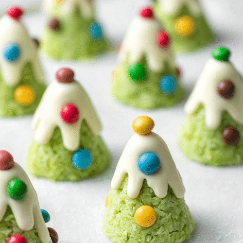 Christmas tree cookies with coconut bases, white chocolate tops, and colorful candy decorations