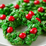 Christmas cookie wreaths made from green cornflake clusters decorated with red candy berries.