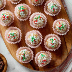 No bake gingerbread cookie balls covered in festive sprinkles arranged on a wooden board.